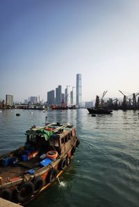 Boats in sea by buildings against clear sky