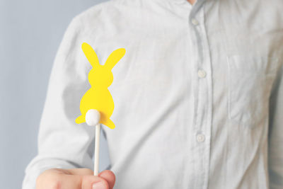 The child holds a yellow figure of a rabbit on a grey background. the trending colors of 2021.