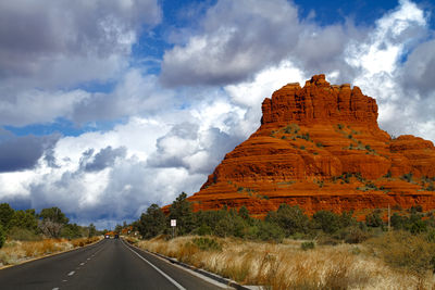 Road against red rocks state park against cloudy sky