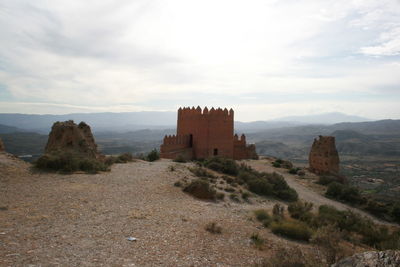 Old ruins on mountain against cloudy sky