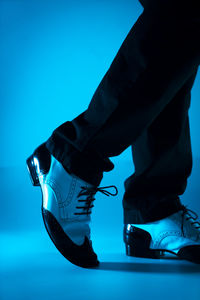 Low section of man standing against blue background