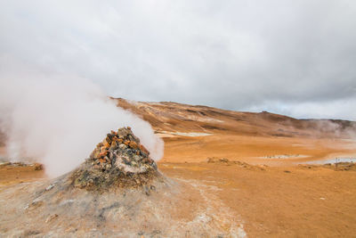 Scenic view of hot spring on mountain against cloudy sky