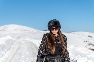 Young woman wearing sunglasses standing against clear sky