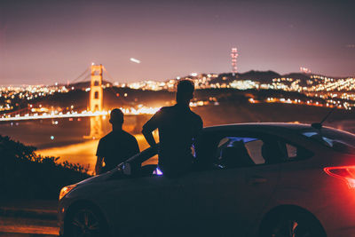 Silhouette people on illuminated bridge against sky at night