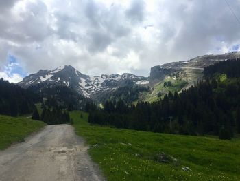 Road amidst plants and mountains against sky