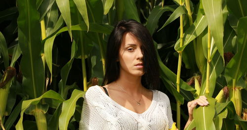 Portrait of beautiful young woman standing against plants