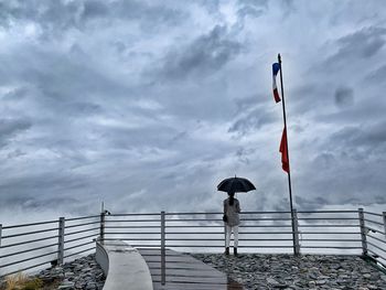 Flag by railing against sky