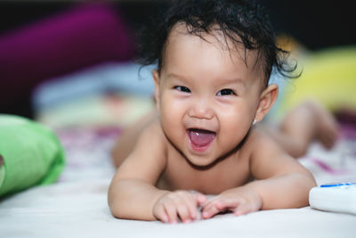 Portrait of cute baby lying on bed at home