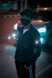 Midsection of man standing by illuminated street light at night