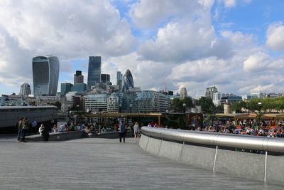 People at city against cloudy sky