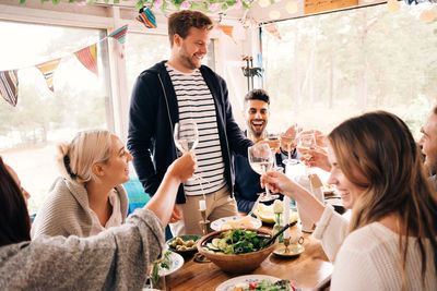Happy man toasting wineglass with friends during lunch party
