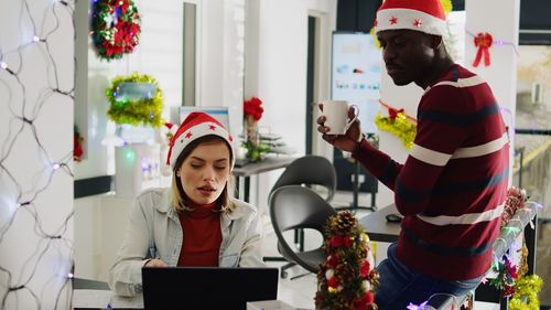 Portrait of female friends using digital tablet while standing against window