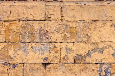 Peeled off old orange paint on flat rough brick wall surface - full frame background and texture