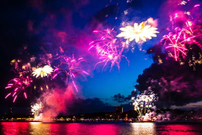 Low angle view of firework display over river at night