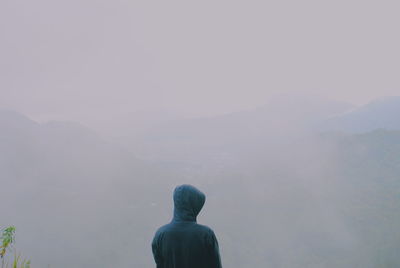 Rear view of woman against mountains in foggy weather