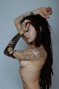 Sensuous naked young woman with tattoo over white background