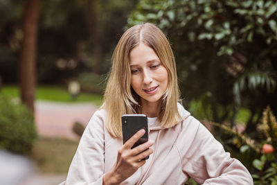 Smiling woman using mobile while standing outdoors