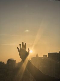 Silhouette person by buildings against sky during sunset