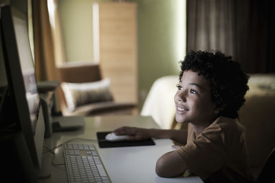 Smiling boy using computer while sitting at home