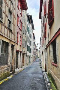 Empty road amidst buildings in city