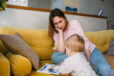 Mom plays at home with a small child on the couch, have fun.