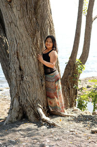 Full length of woman with tree trunk