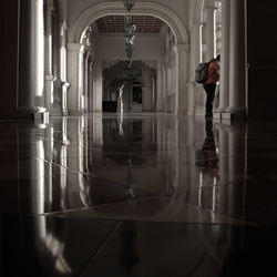 Reflection of woman standing in corridor of building