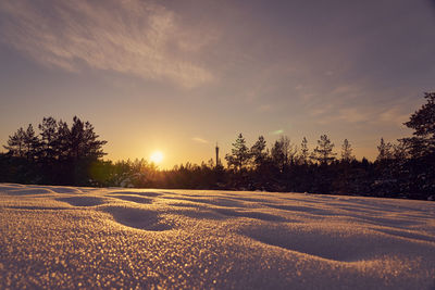 Scenic view of snow covered field against sky during sunset