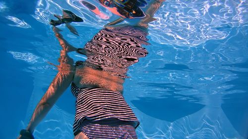 Rear view of young woman holding weights swimming in pool