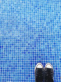 Low section of person wearing canvas shoe standing on floor