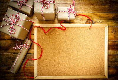 Directly above shot of gifts by blank bulletin board on table