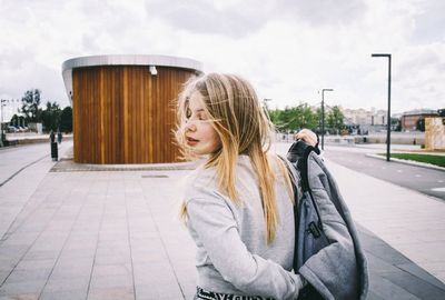 Rear view of a young woman with windy blonde hair outdoors