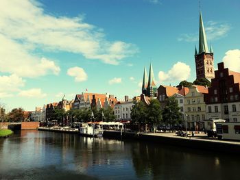 View of buildings at waterfront against cloudy sky