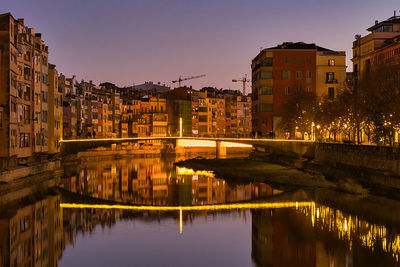 River by illuminated buildings against sky at night