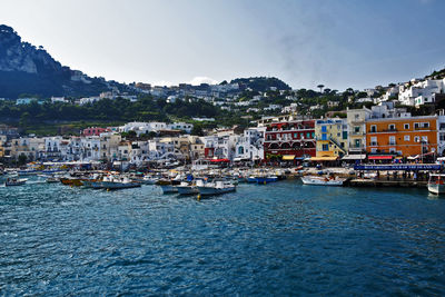 Boats moored at harbor in city against clear sky