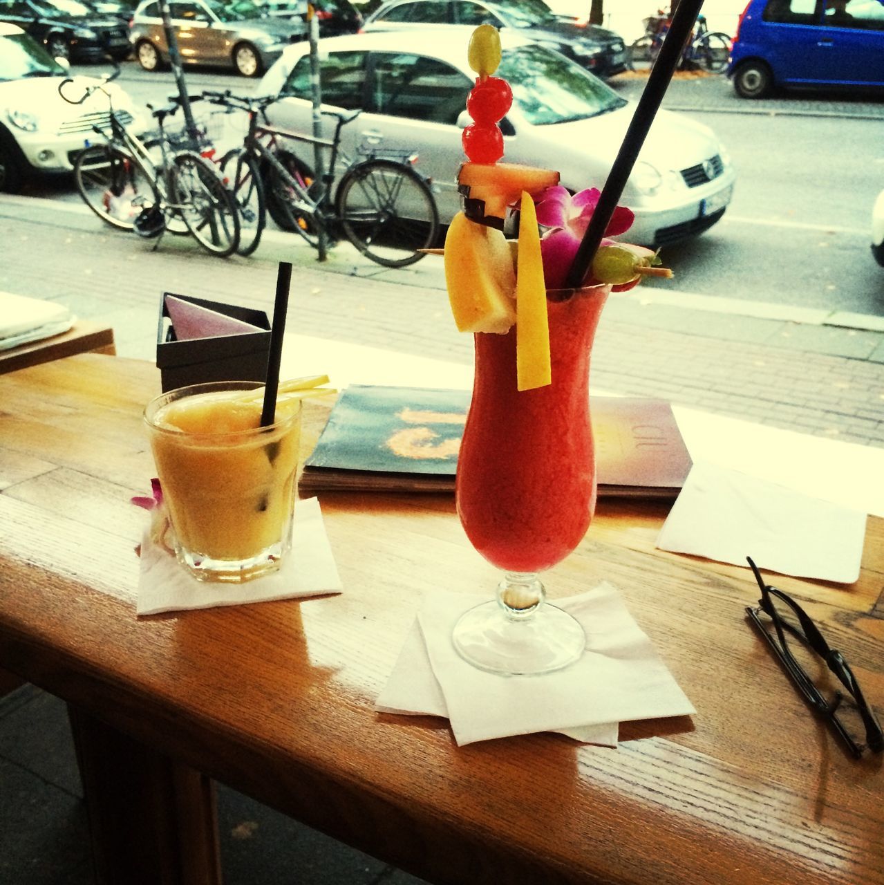 table, food and drink, drink, freshness, still life, indoors, chair, drinking glass, restaurant, refreshment, spoon, drinking straw, wood - material, cocktail, sunlight, high angle view, absence, sidewalk cafe, food, healthy eating