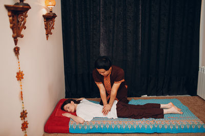 Rear view of man looking away while relaxing on bed at home