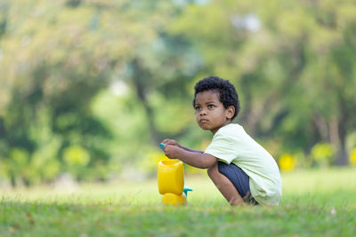 Side view of boy playing with bottle on field