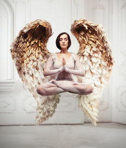 Full length of woman with wings levitating against wall