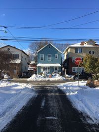 Road by houses against clear sky during winter