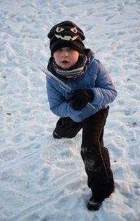 High angle portrait of boy playing with icicle on snow