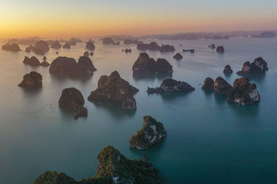 Rocks in sea against sky during sunset