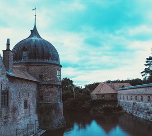 Buildings by river against sky