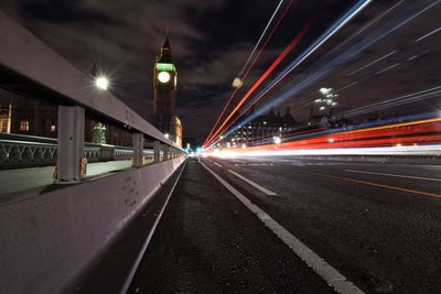 Light trails on road in city against sky at night