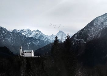 Distant view of historic church on mountain against sky during winter