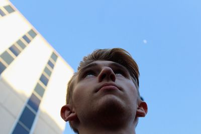 Low angle view of man looking up against blue sky