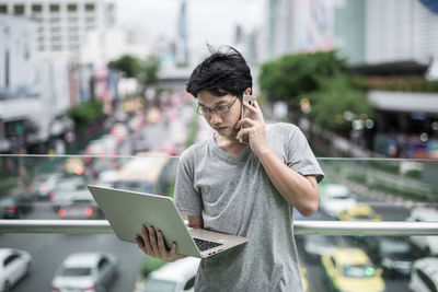 Young man using mobile phone in city