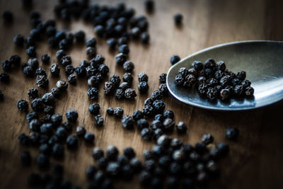 Close-up of black pepper with spoon on wooden table