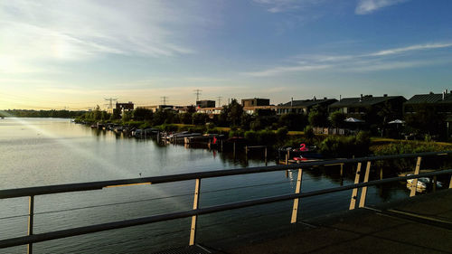 Scenic view of river by buildings against sky during sunset