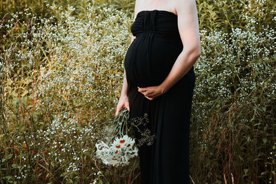 Pregnant woman hugging her tummy standing outdoors surrounded by nature. pregnancy, expectation